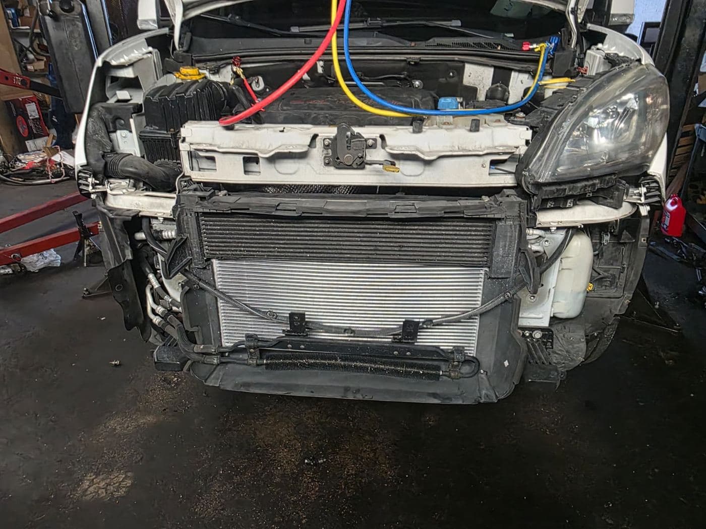 Car with the front open and gauge hoses connected to recharge the air conditioning