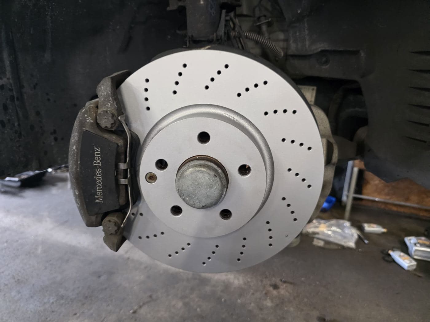 New drilled brake rotor with its caliper, installed in the shop