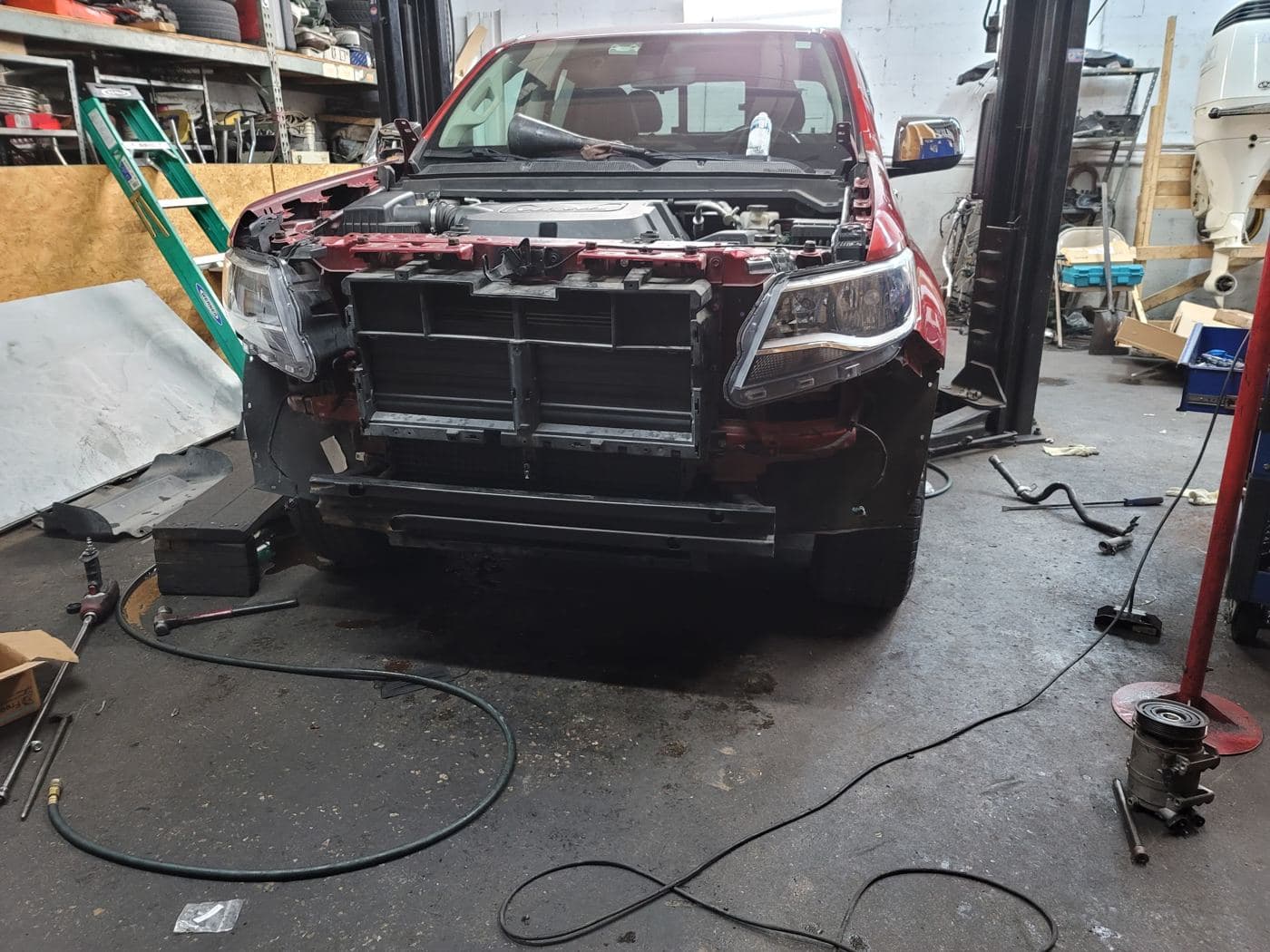 Red pickup with the front end taken apart inside the shop